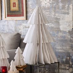 two white paper christmas trees sitting on top of a table next to a gray couch