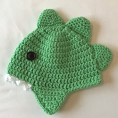 a crocheted green mitten with a black button on the front and bottom