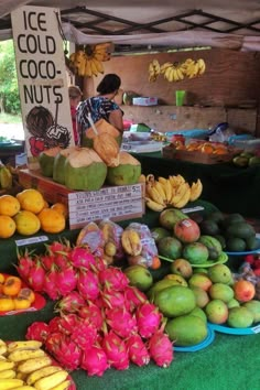 there are many different types of fruit on display at this market stall, including bananas, pineapples, and coconuts