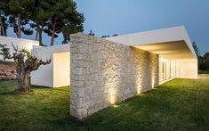 an exterior view of a modern house with stone walls and green grass in the foreground