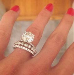 a woman's hand with two wedding rings on it and one diamond ring in the middle