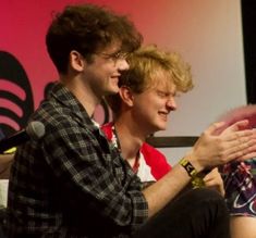 two young men sitting next to each other on stage