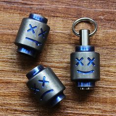 two metal key chains sitting on top of a wooden table