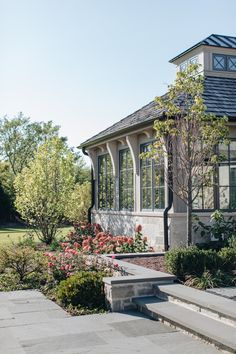 a house with steps leading up to it and flowers growing in the front yard area