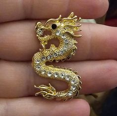 a gold dragon brooch sitting on top of a person's hand