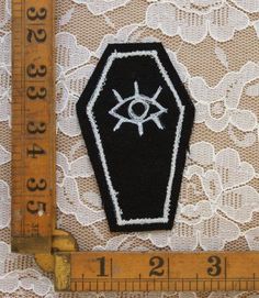 a black and white patch with an eye on it next to a measuring tape,