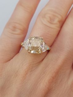 a woman's hand with a yellow and white diamond ring on top of it