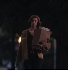 a woman is walking down the street with a box on her shoulder and looking at something