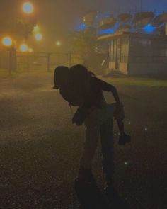 a man riding a skateboard down a street next to a parking lot at night