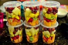 four plastic cups filled with different types of fruit