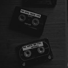 two black and white cassettes sitting on top of a wooden table next to each other