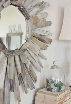 a mirror sitting on top of a wooden table next to a lamp and bookcase