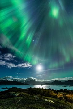 the aurora bore is shining brightly in the night sky over an island and body of water