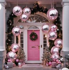 a pink front door decorated for christmas with silver and pink ornaments hanging from the ceiling