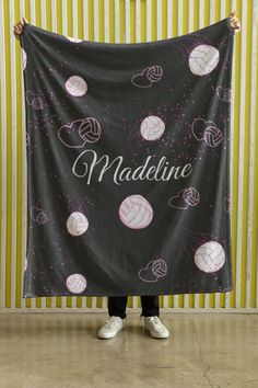 a woman holding up a black and pink blanket with the words madline on it