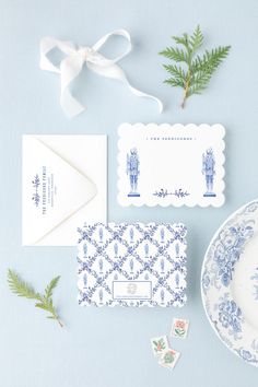 the wedding stationery is laid out on a blue background with greenery and place cards