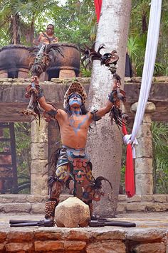 a man with painted face and body is standing in front of a tree holding two chains