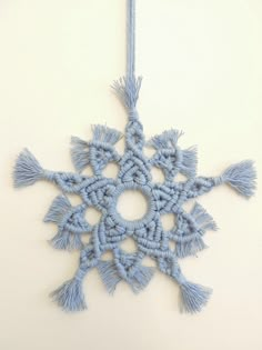 a blue snowflake ornament hanging from a string on a white wall