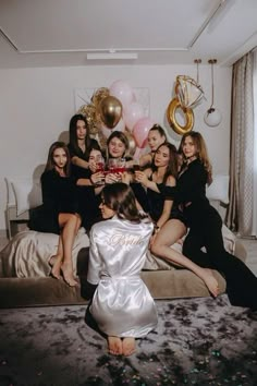 a group of women sitting on top of a bed in front of balloons and confetti