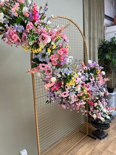 a bunch of flowers that are sitting on a stand in front of a window with curtains