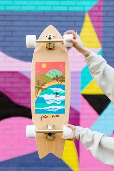 a person holding a skateboard in front of a colorful wall