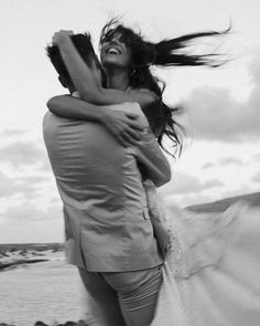 black and white photograph of woman hugging man on beach