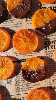 oranges are arranged on top of a newspaper with chocolate frosting and sprinkles