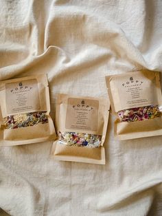 three bags of tea sitting on top of a bed