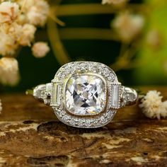 an engagement ring with a cushion cut diamond surrounded by smaller baguettes and pave diamonds