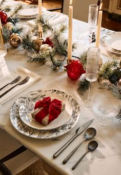 the table is set for christmas dinner with silverware and candles