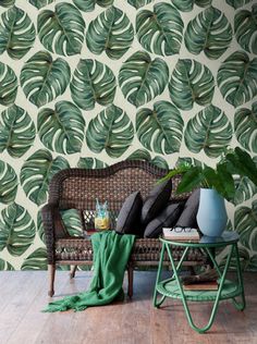 a living room with a wicker couch and wallpaper that has green leaves on it