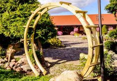 a wooden arch in the middle of a garden with rocks and flowers around it,