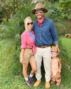 a man and two women standing next to each other in front of some trees, grass