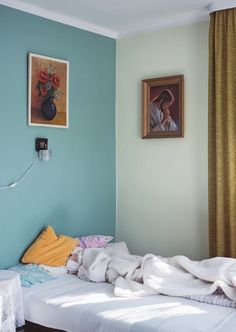 a bed with blankets on top of it next to a window and pictures hanging on the wall