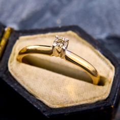 a close up of a gold ring with a diamond on it's side in a case