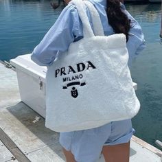 a woman carrying a white bag on top of a dock