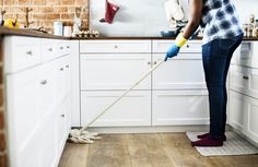 a woman is cleaning the kitchen with a mop