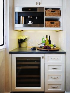 a small kitchen with white cabinets and black counter tops, wine glasses on the bar