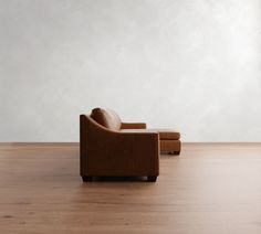 an empty room with a chair and footstool on the floor in front of a white wall