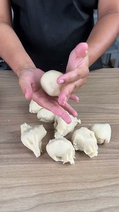 a person is making dumplings on a wooden table