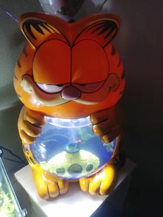 an orange and black cat statue next to a fish bowl