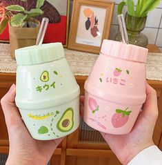 two hand holding cups with straws and avocado designs on them, one is pink and the other is green