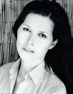 a black and white photo of a woman with long dark hair wearing a dress shirt