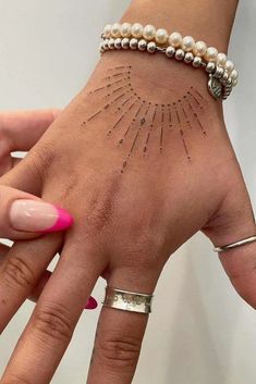 a woman's hand with tattoos on it and two bracelets around her wrist