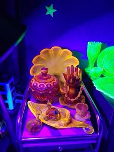 there are many items on the table with purple lights in the background and green leaves