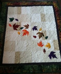 a quilted table runner with leaves on it