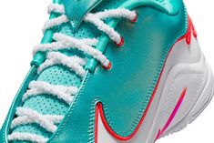 the nike air zoom tennis shoe is turquoise and white with red accents on the upper part