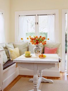 a table with flowers in a vase on top of it next to a couch and window