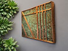 a green plant sitting on top of a wall next to a metal window pane