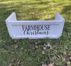 a wooden sign that says farmhouse christmas on it in the grass with leaves around it